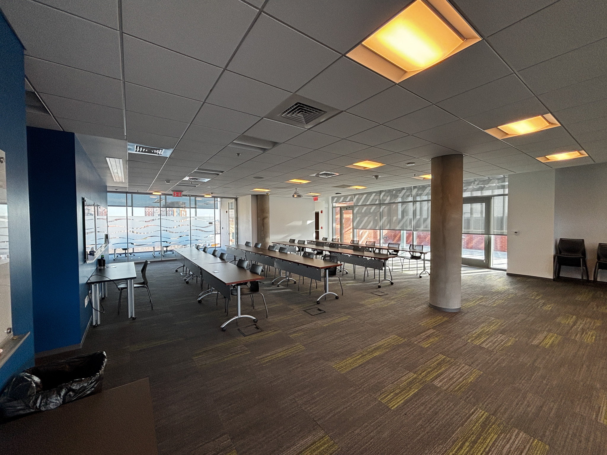 Wide angle photo of a conference room space set up classroom style with rows of tables.