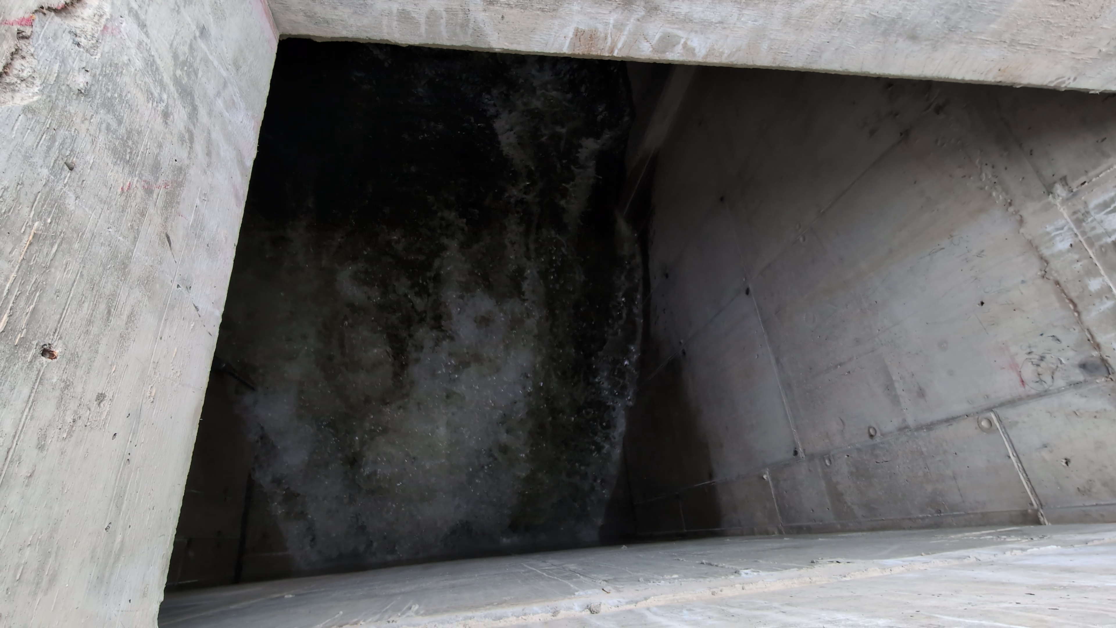 Birds-eye view of water flowing down a dark tunnel.